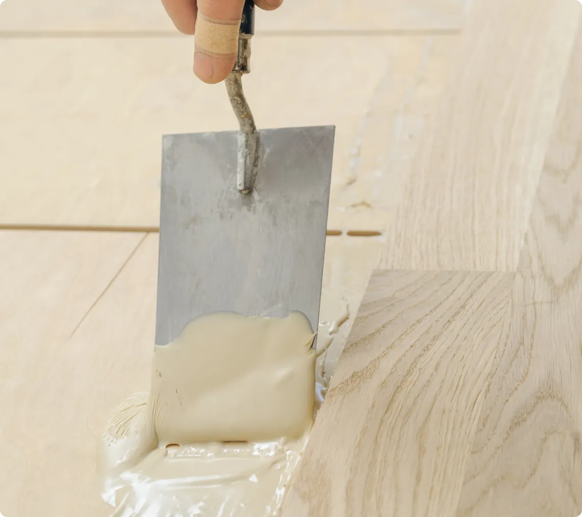 Applying wood filler to a wooden surface with a trowel during repair work